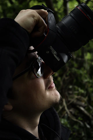 A candid shot of a photographer adjusting their camera in natural light outdoors.