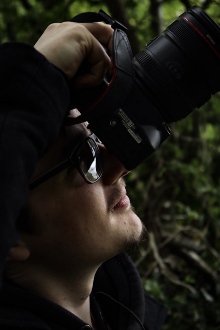 A candid moment of a creator filming content outdoors, with natural sunlight highlighting their focused expression.