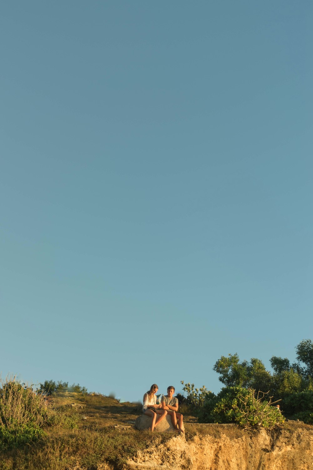 a couple of people sitting on top of a hill