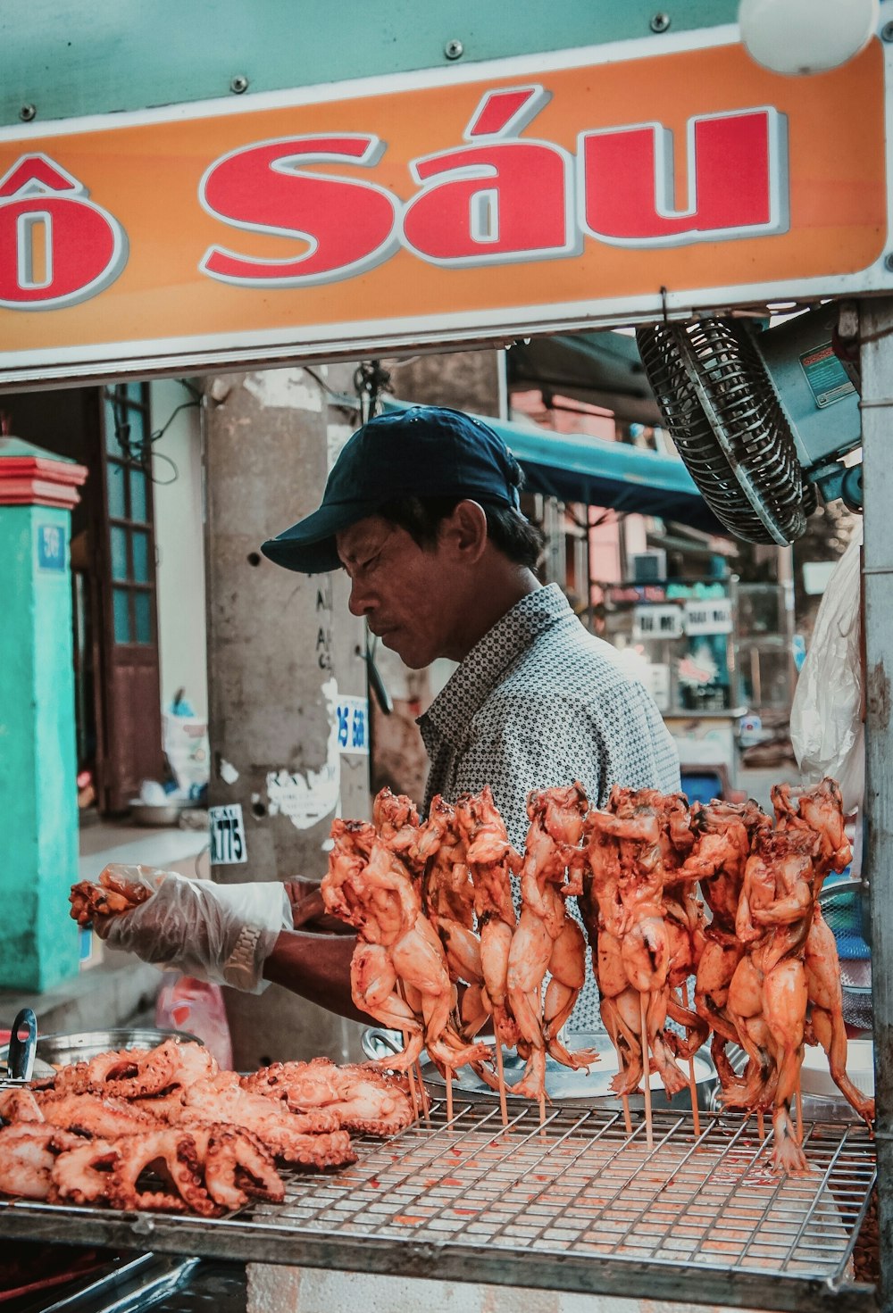 a man cooking chicken on a grill in front of a store