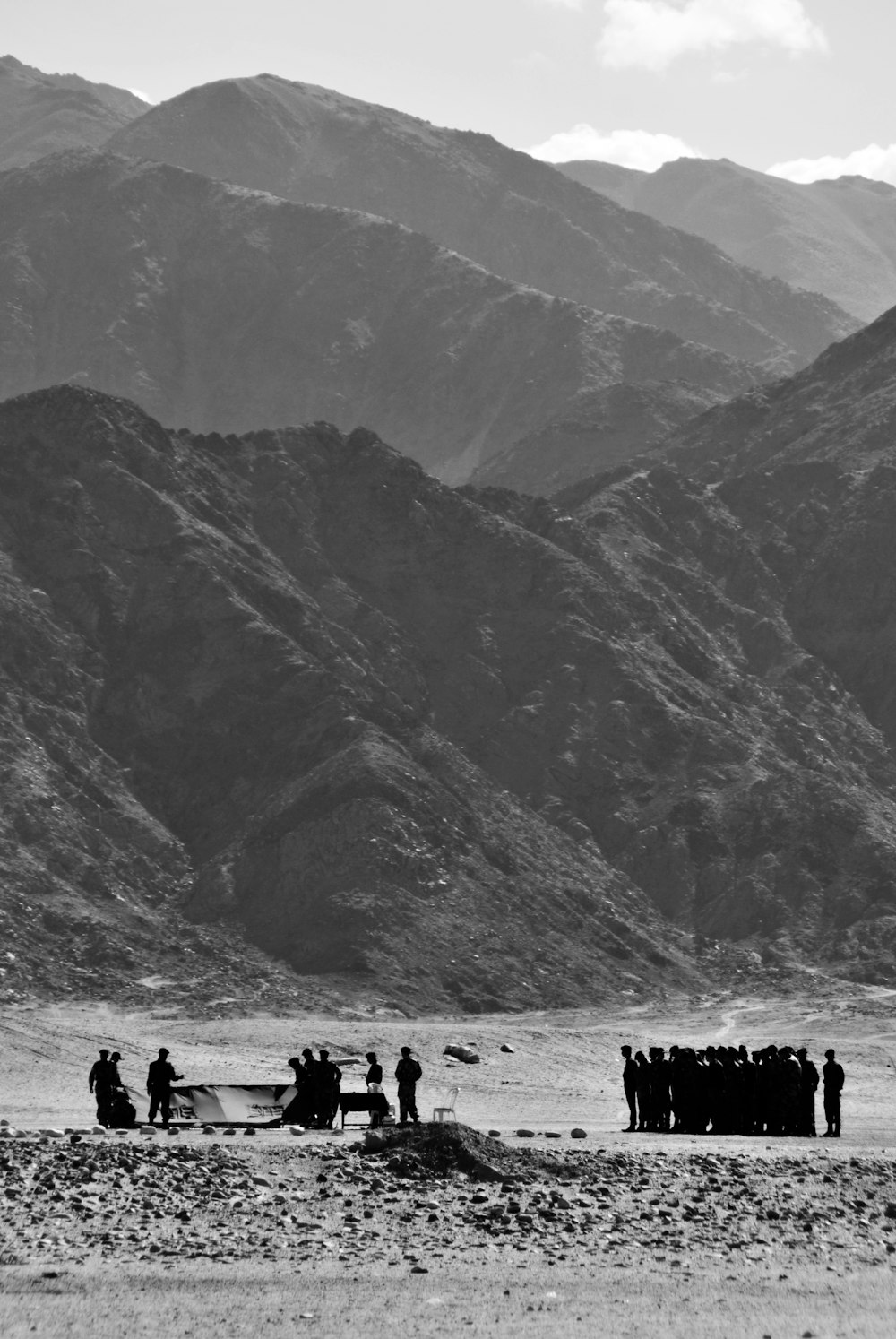grayscale photo of people gathering near mountain