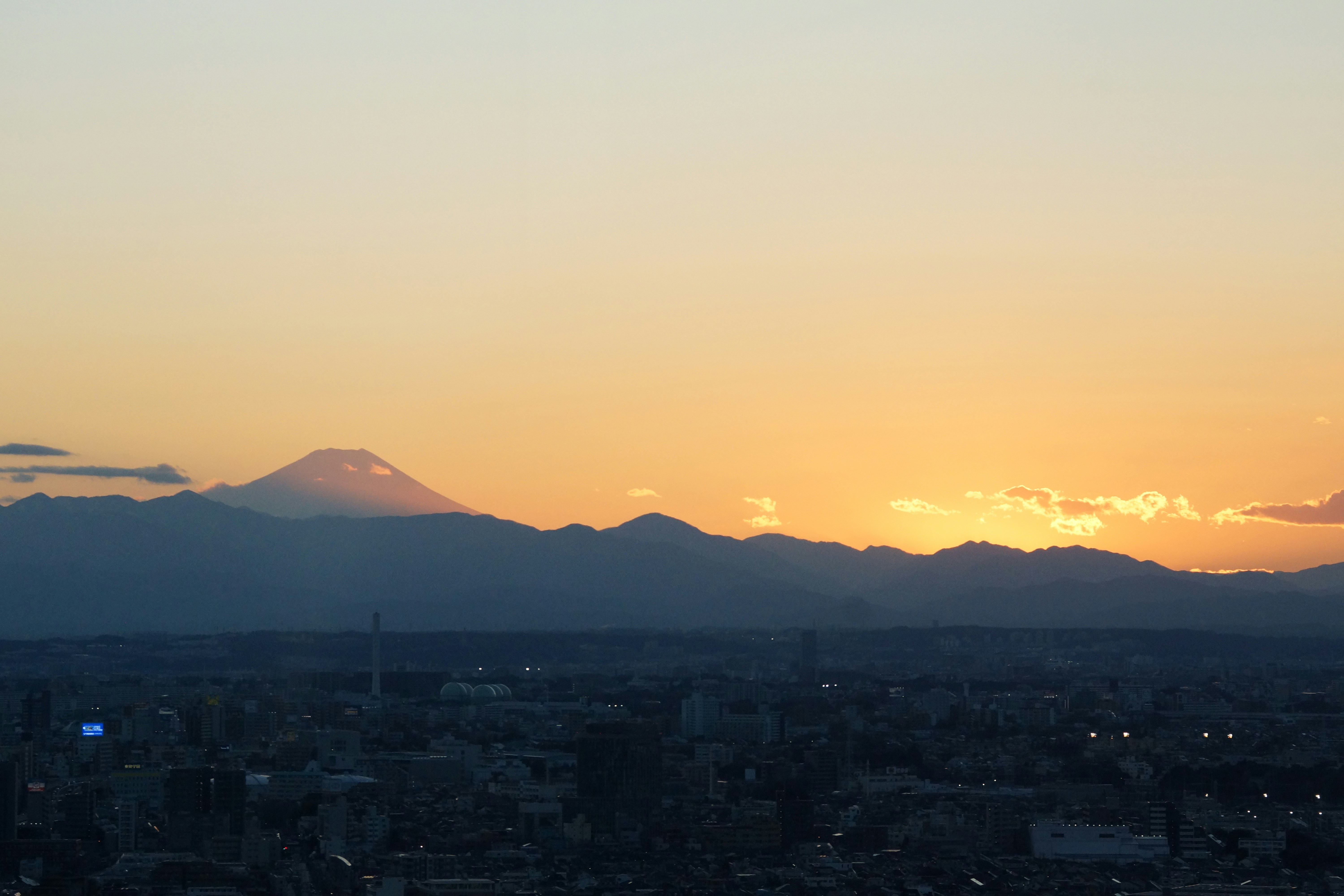 Tokyo skyline at golden hour with Mount Fuji, dramatic well-lit cityscape, open sky