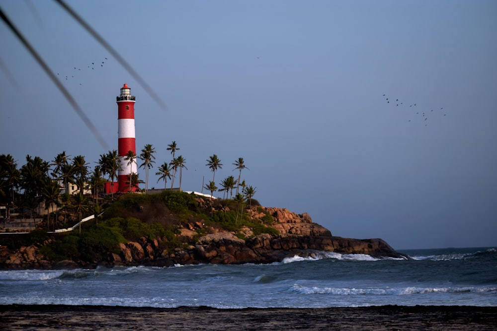 red and white lighthouse near ocean