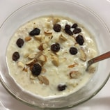 Creamy shrikhand served in a bowl garnished with saffron strands and pistachios.