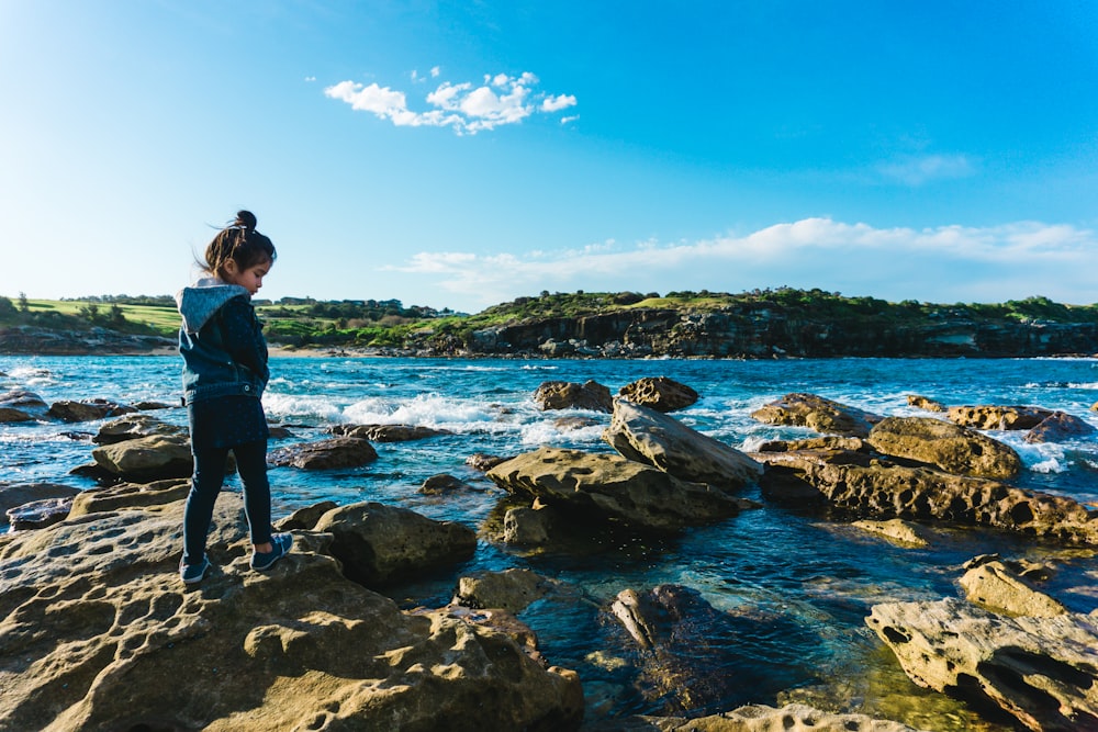 girl standing on rock near river