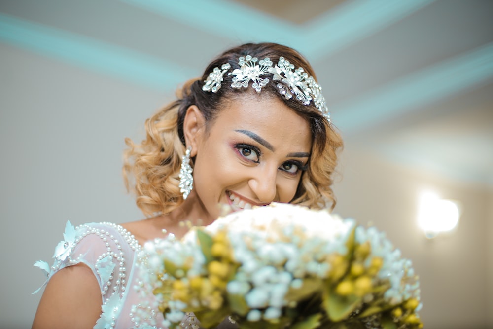 smiling woman in white wedding dress with bunch of white flowers