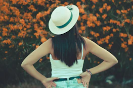woman wearing white hat facing flowers