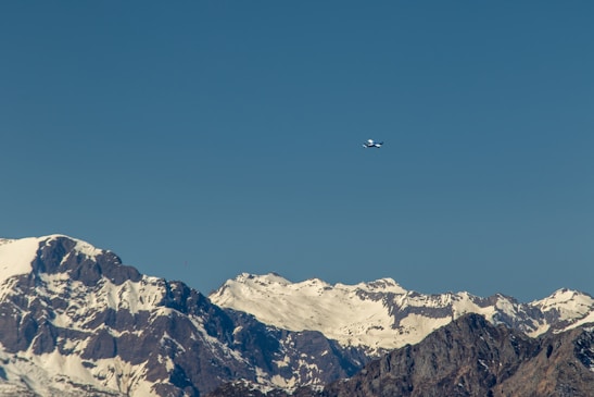 An airplane flying over a mountain range with clear skies.