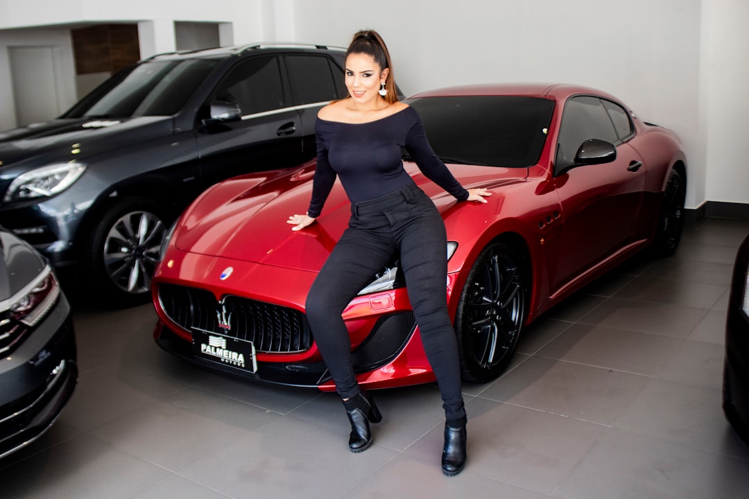 woman leaning on red Maseratti car