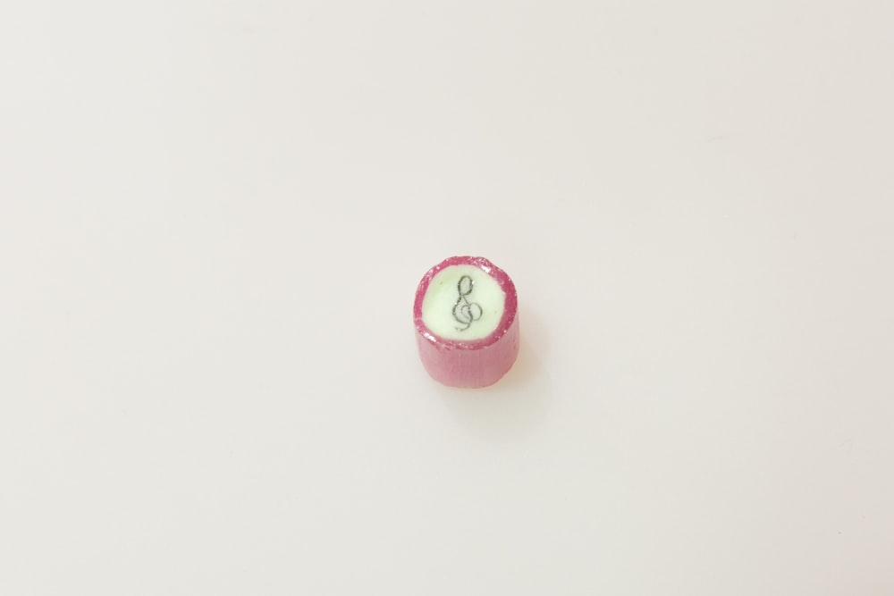 a pink pill with a green letter on it