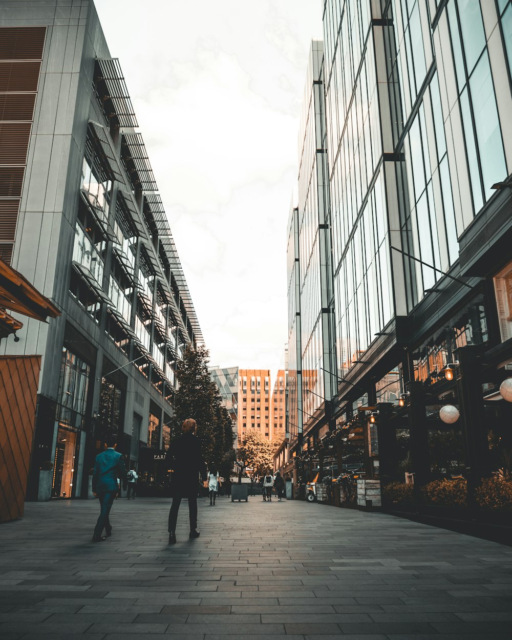 two person walking between buildings