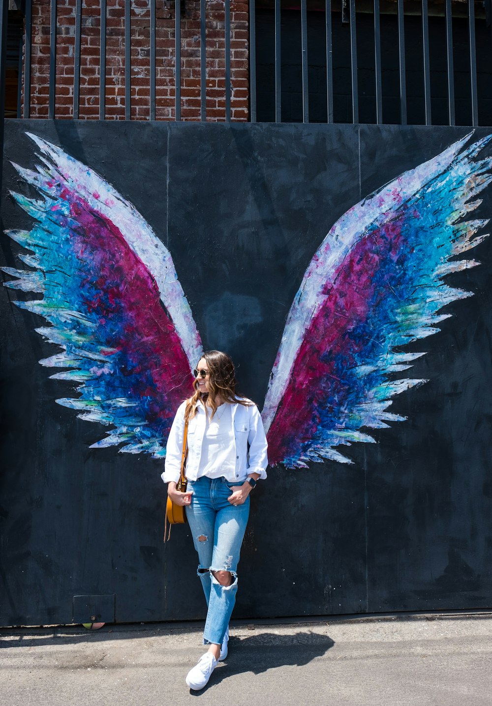 woman standing near wing graffitti