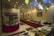 An indoor restaurant setting featuring a buffet arrangement with an assortment of dishes, plates, and cutlery. The room is decorated with small flags, red table skirts, and ornamental lighting. A table is set with various fruits and vegetables, and the wall is adorned with framed artwork.