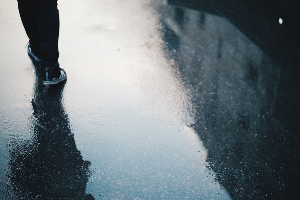 a person standing on top of a wet sidewalk