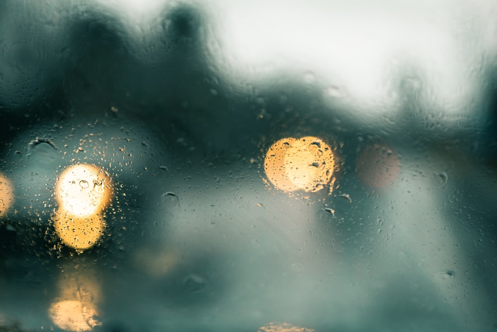 a rain covered window with street lights in the background