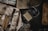 A collection of vintage military items including a ration pack, a black grenade, a bar of soap, a shaving brush, cutlery wrapped in cloth, matches, and a tin box. The items are arranged on a dark surface, suggesting a historical or military theme.