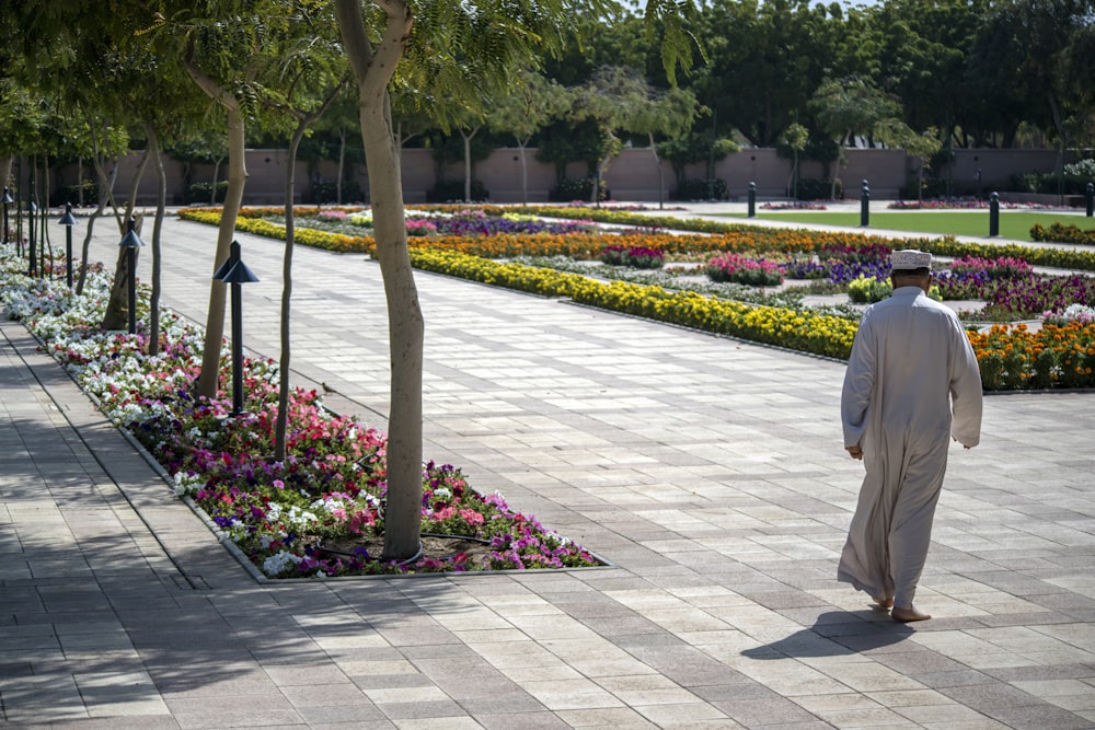 man wearing thawb walking near plant