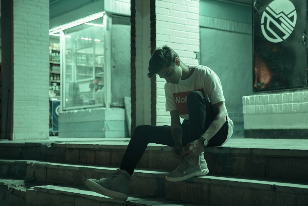 man sitting on stairway during nighttime