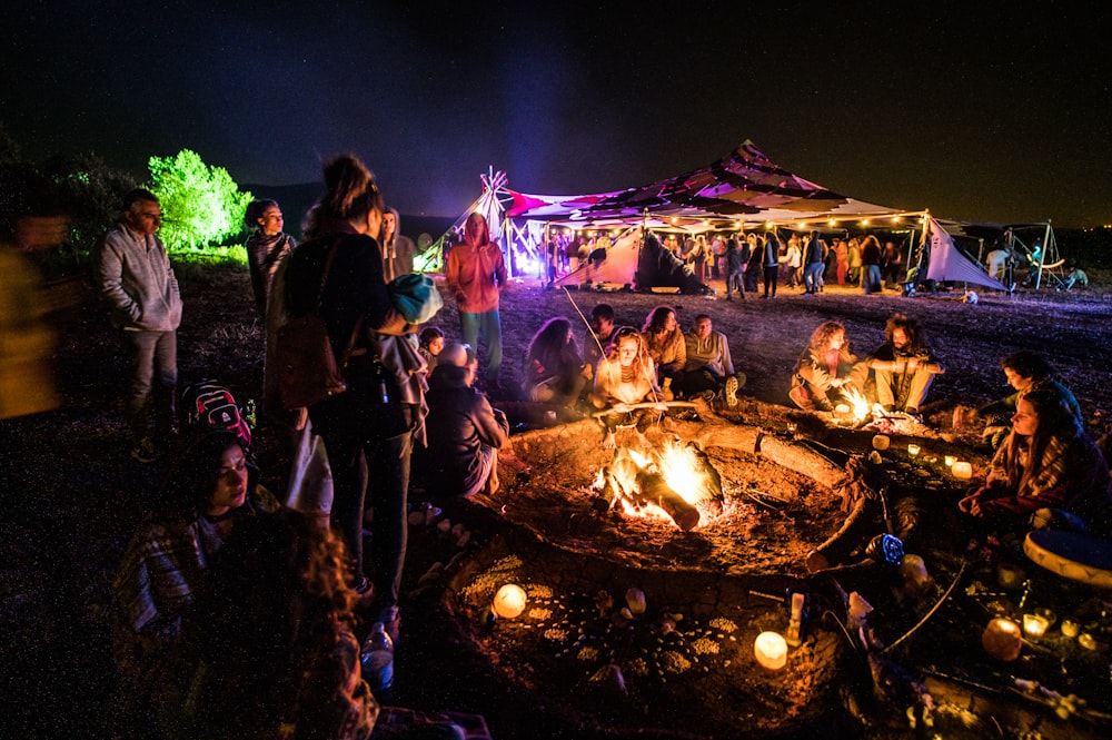 people sitting and standing beside bonfire during night time