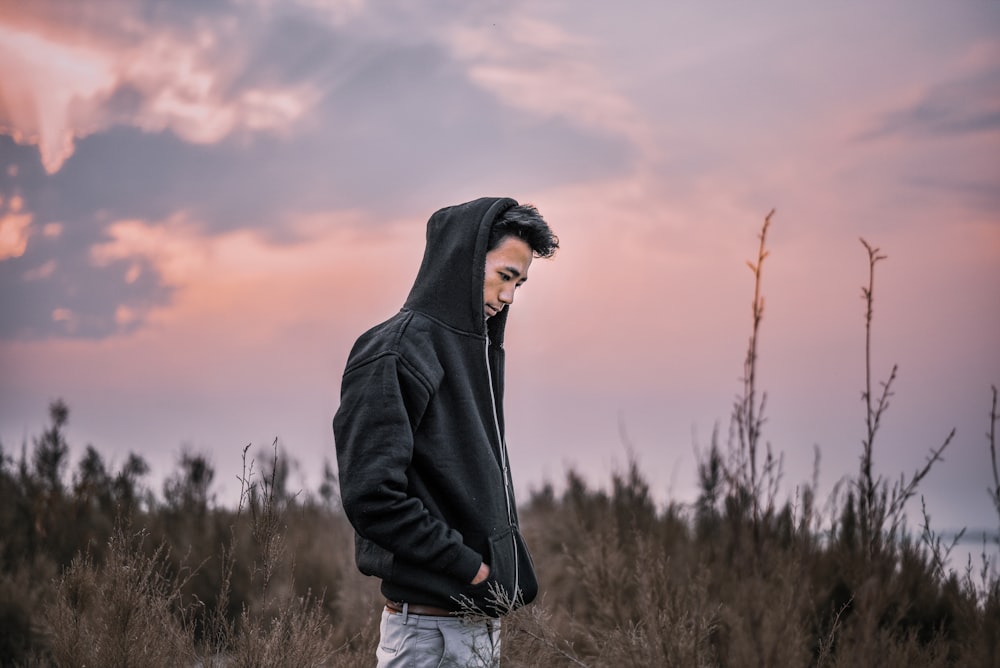 man in black hoodie standing on grass field