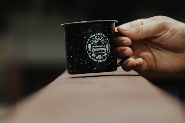A close-up of a nature-inspired mug with inspirational mountain graphics on a wooden table.