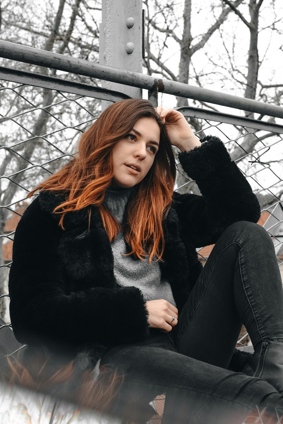 close-up photo of woman leaning on chain link fence during daytime