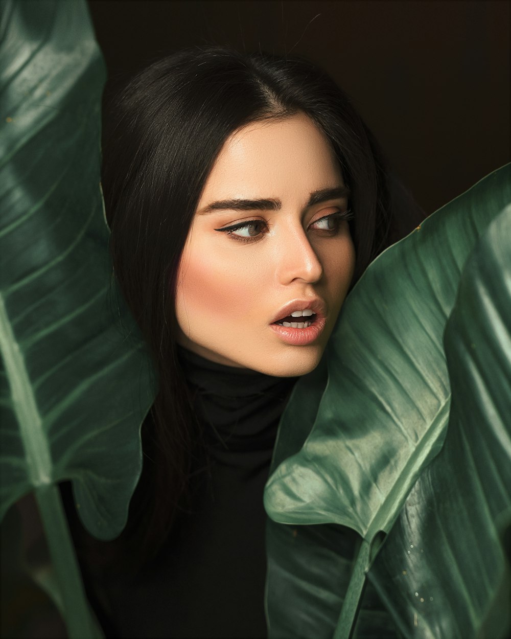 close-up photography of woman beside green leaves