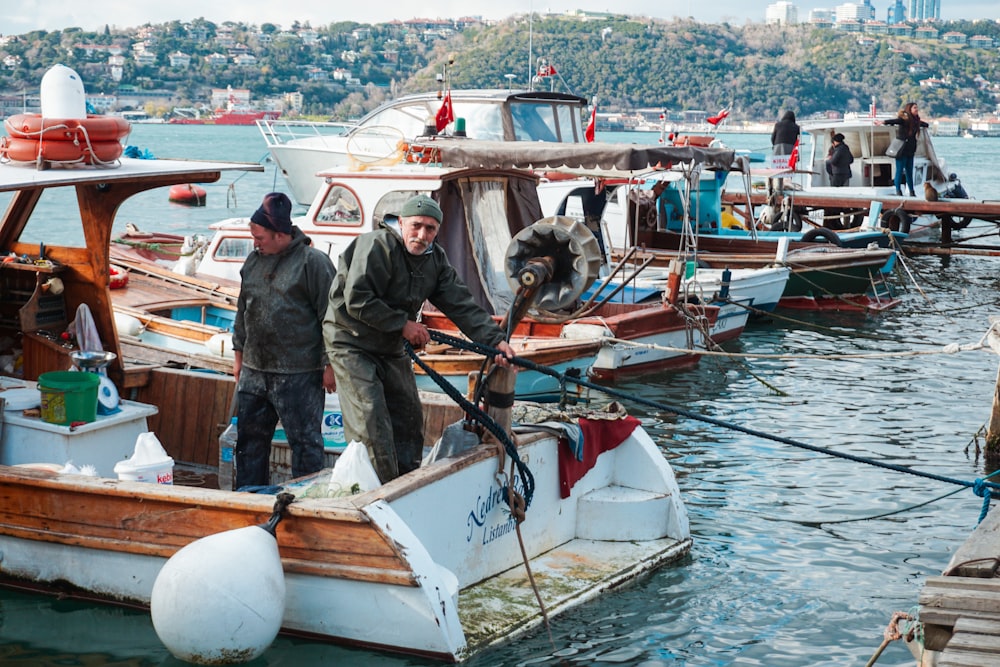 two men riding in boat while holding rope at daytime