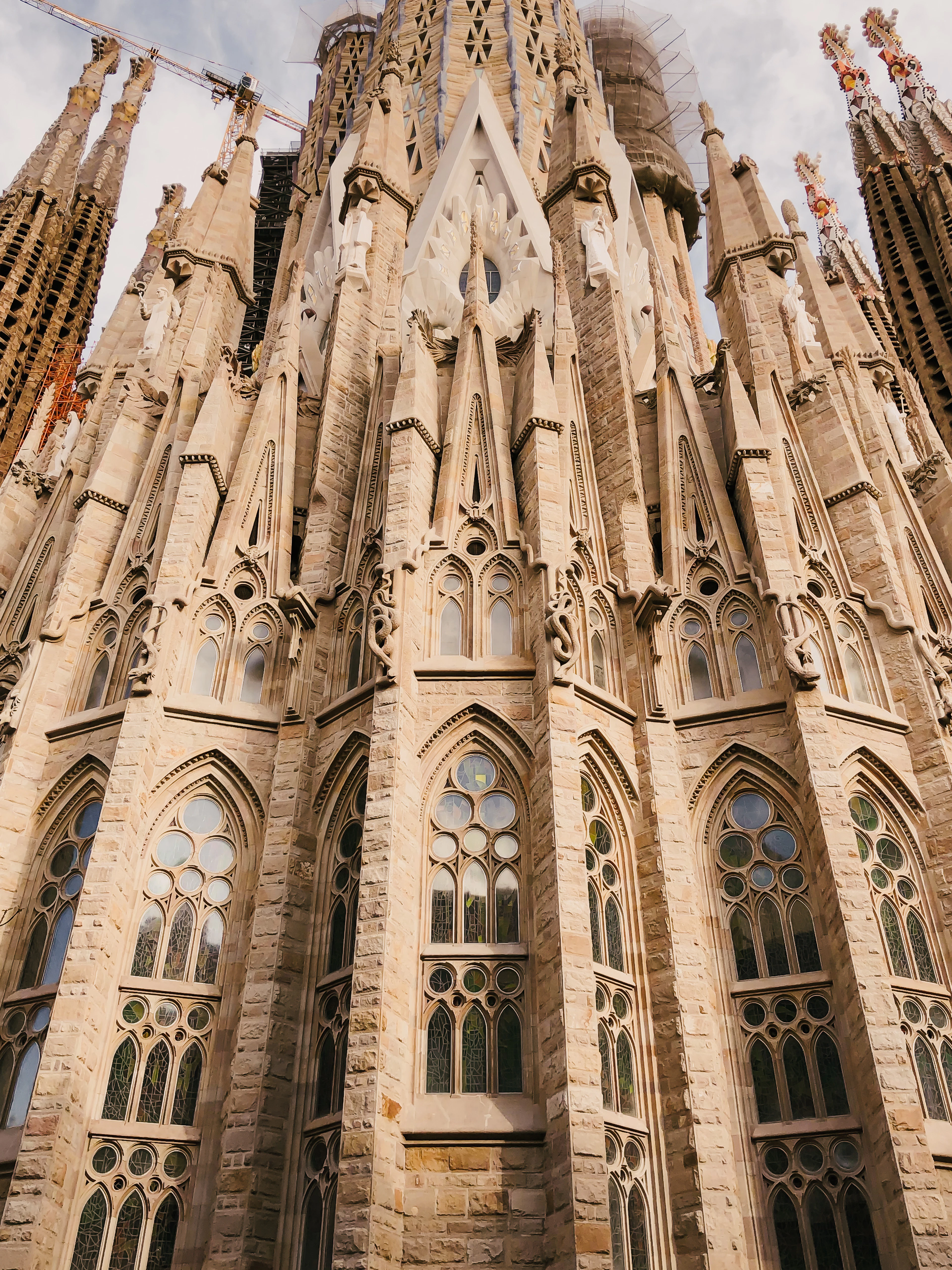 A dramatic low angle up the Sagrada Familia's carved stone facade and spires against the sky.