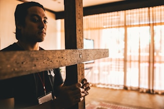 A confident Christian business owner reviewing plans in a modern office, with a subtle cross in the background.
