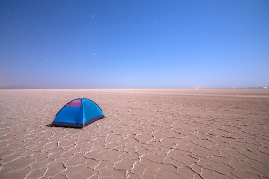 blue dome tent on brown open-field during daytime in Qom Province Iran