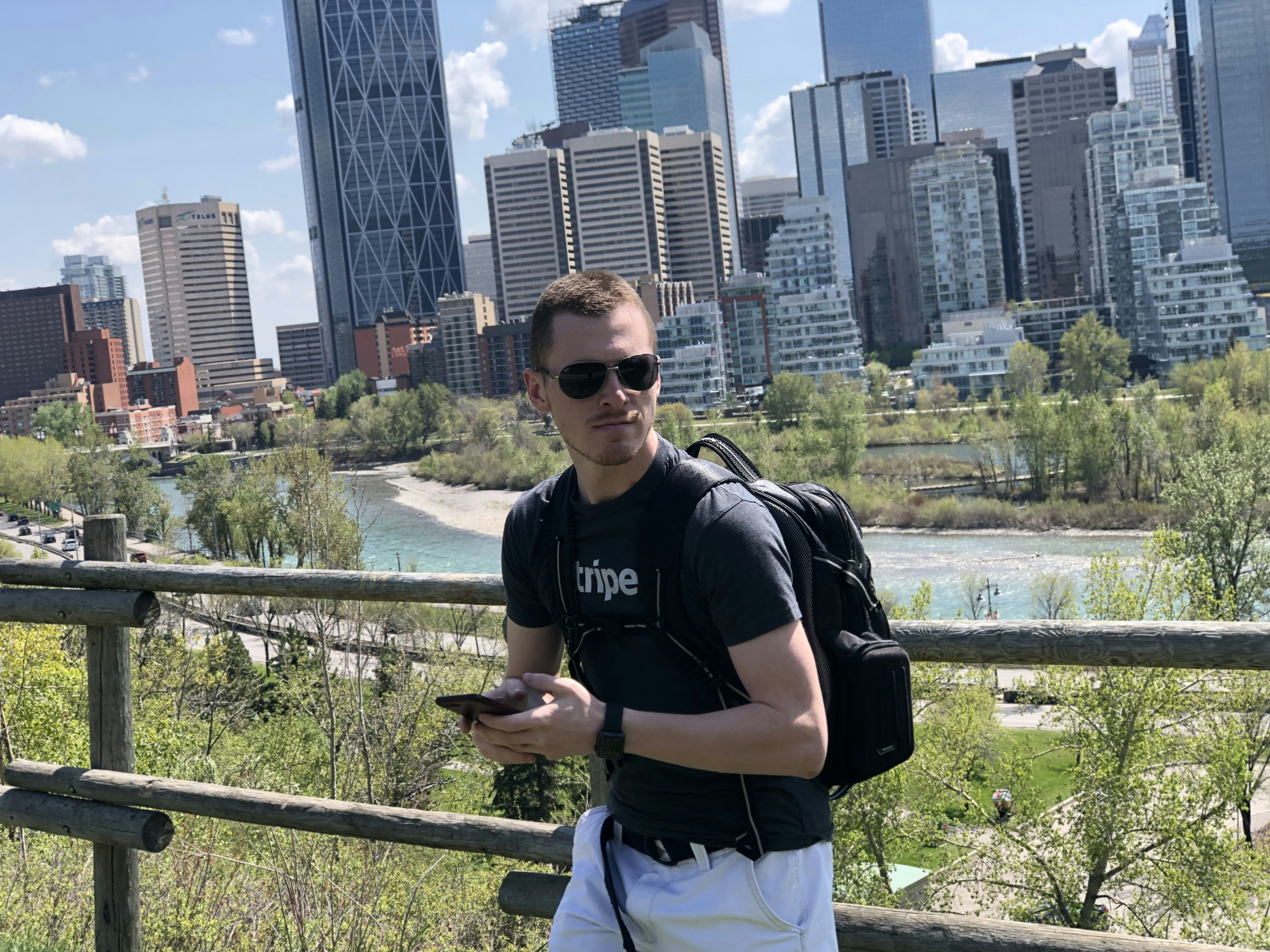 man looking to her left while holding smartphone, City(e)scape - Adventuring along the City of Calgary