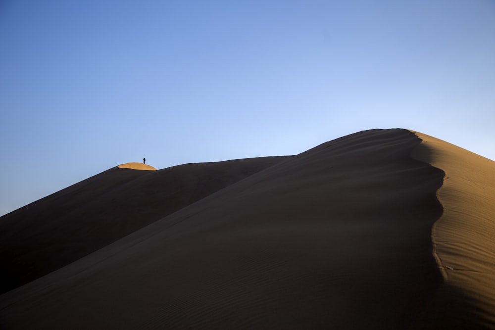 person standing on sand hill