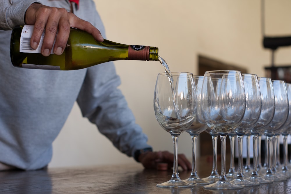 man pouring champagne on clear drinking glass