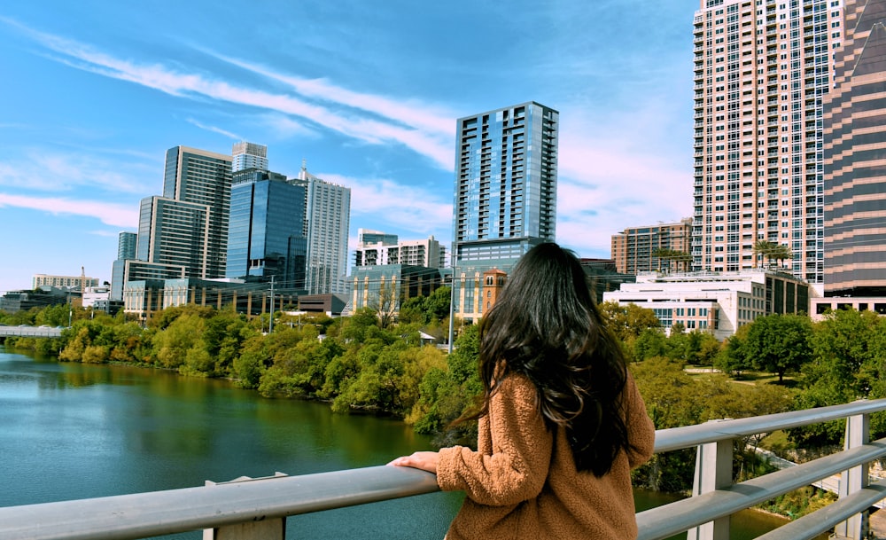 woman holding handrail overlooking cityscape during daytime
