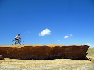 Cyclist riding on a dusty trail through the Negev desert under a clear blue sky.