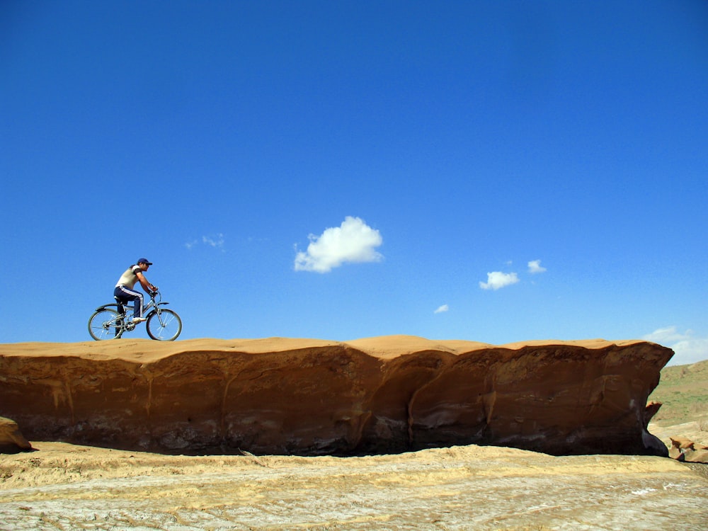 man riding bike on rocky mountain during day