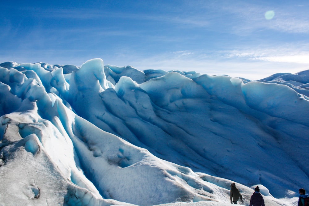 three people walking on snow during daytime