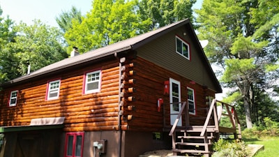 A rustic cabin surrounded by trees, featuring a freshly painted exterior in warm tones.