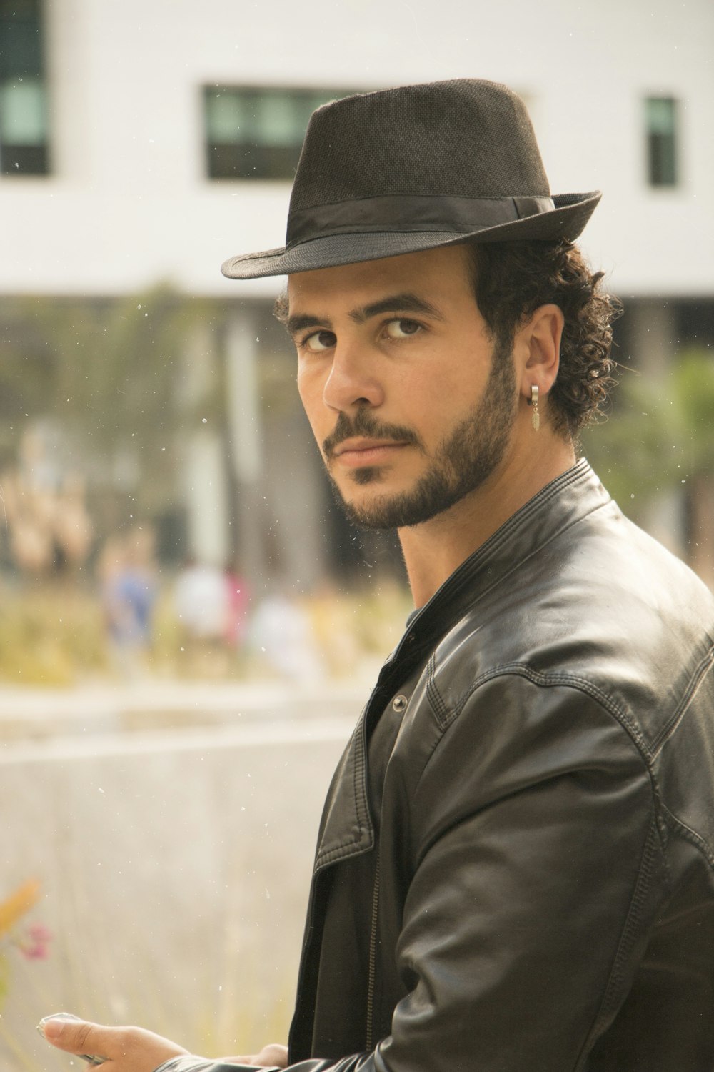 man in grey leather jacket and black hat looking over left shoulder