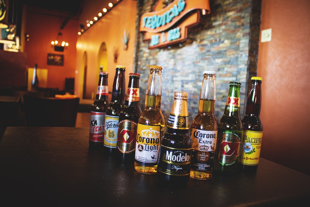 eight beer bottles on brown table inside bar