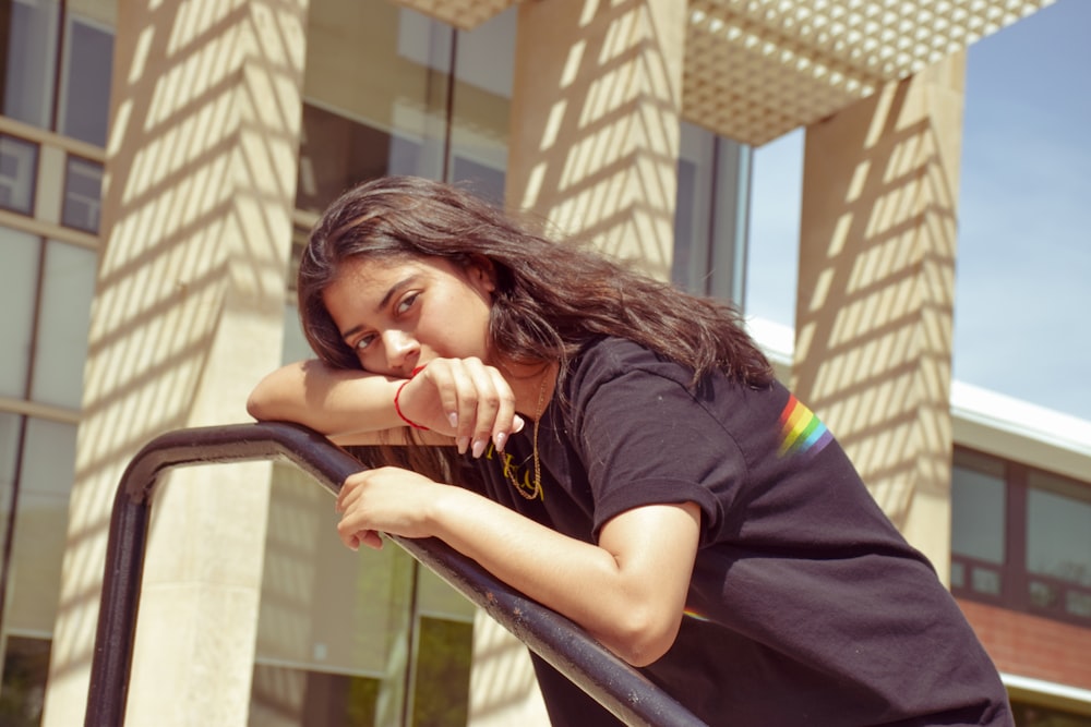 woman leaning her face on black metal railings