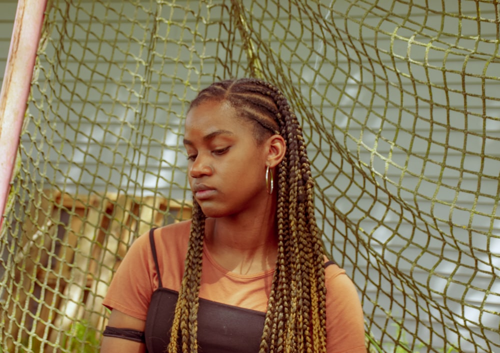 woman wearing orange and black top standing in front of green net