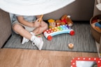 child sitting on floor and playing with xylophone toy