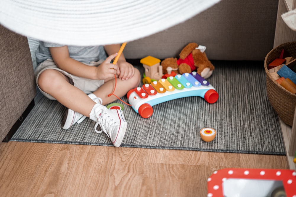 child sitting on floor and playing with xylophone toy