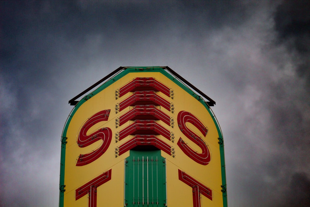yellow and green signage under heavy clouds