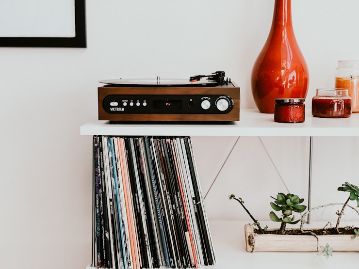Wooden Victrola record player on white table about a collection of records.