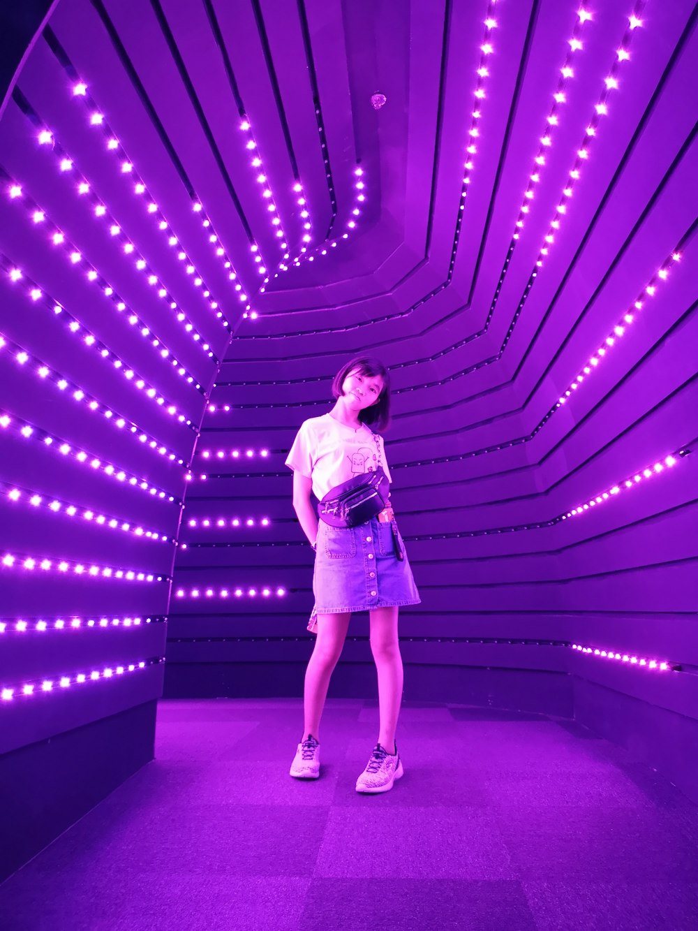 woman standing in middle of purple lighted passage