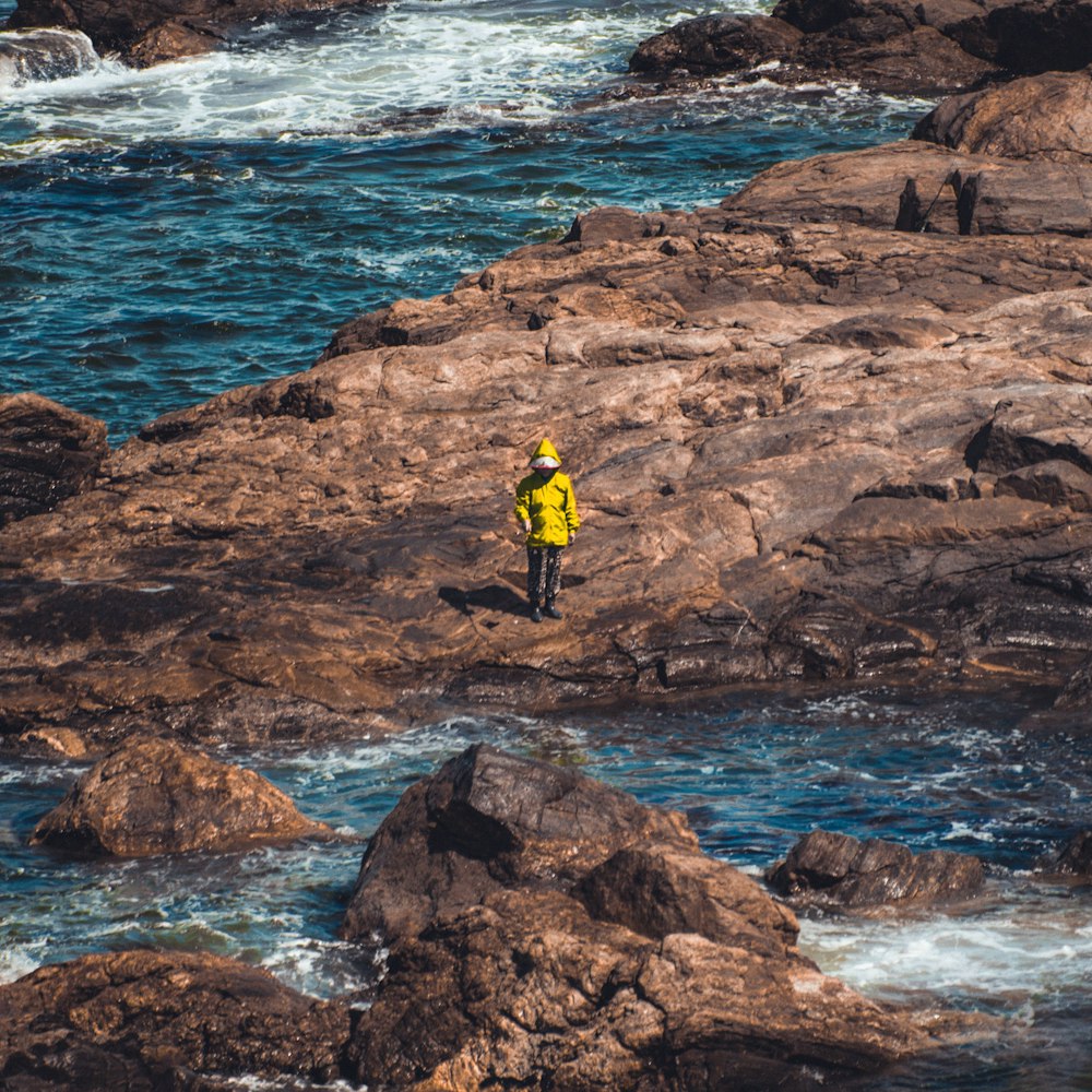 Persona con abrigo amarillo de pie frente a un cuerpo de agua