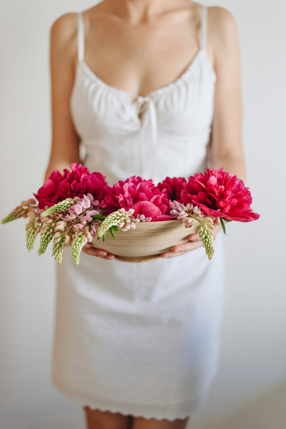 woman in white dress carrying red flowers